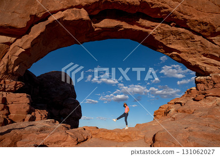 Asian female tourist standing at the center of North Window in Arches National Park, Utah, USA 131062027