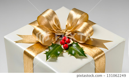 A close-up of a gift box wrapped in white or light cream paper and tied with a gold ribbon. A fluffy bow is tied at the top. The center of the bow is adorned with a sprig of mistletoe or holly with re A close-up of a gift box wrapped in white or light cream paper and tied with a gold ribbon. A fluffy bow is tied at the top. The center of the bow is adorned with a sprig of mistletoe or holly with re 131062249