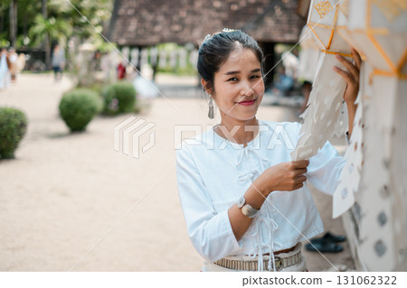 A woman in traditional clothing participates in a cultural activity outdoors, showcasing heritage and joy. 131062322