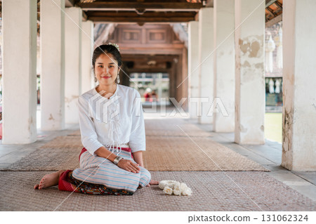 A woman in traditional attire sits in a historic architectural setting, showcasing cultural heritage and serene ambiance. 131062324