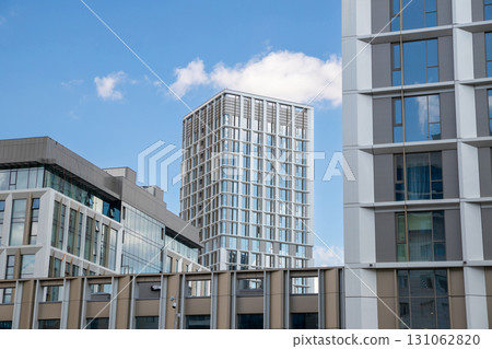 Skyscrapers and contemporary buildings rise prominently against a bright blue sky, showcasing sleek designs and modern materials in a bustling cityscape. 131062820