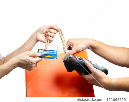 Close up of hands using credit card payment via POS terminal while holding orange shopping bag, concept of cashless transaction, retail, finance, e-commerce, shopping, and modern digital lifestyle 131062853