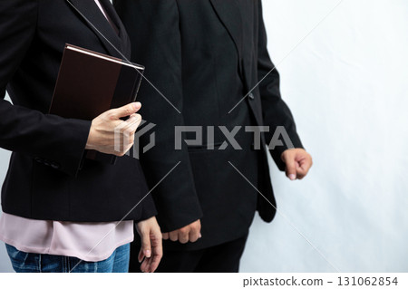 Business people in black suits standing together, one holding notebook for meeting, concept of teamwork, corporate collaboration, leadership, professional lifestyle, office, management, and 131062854