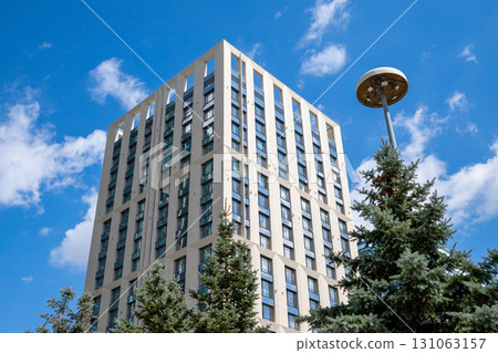 Modern architectural building under a clear blue sky with lush blue spruce trees nearby and modern street lamp. urban landscape's contemporary architecture, improvement, beautification, renovation 131063157