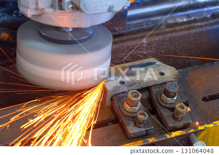 Industrial grinder creating sparks polishing metal detail on metalwork plant. 131064048