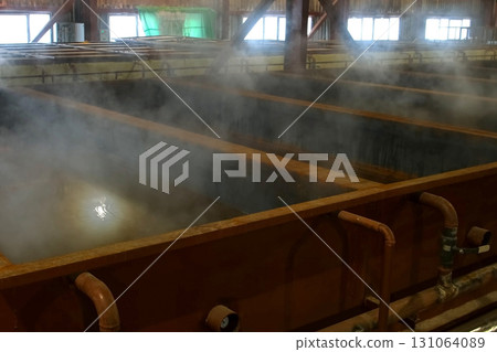 Steam escaping from hot water tanks in woodworking factory workshop. Steam escaping from hot water tanks in woodworking factory workshop. 131064089