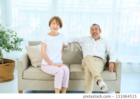 A middle-aged couple sitting on the sofa. 131064515