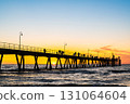 Stunning sunset at Glenelg Beach jetty, with silhouettes of people 131064604