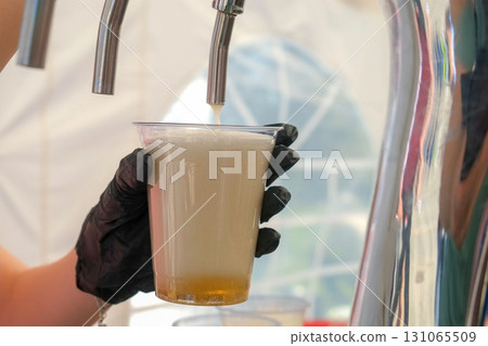 Bartender pouring beer into plastic cup montage 131065509