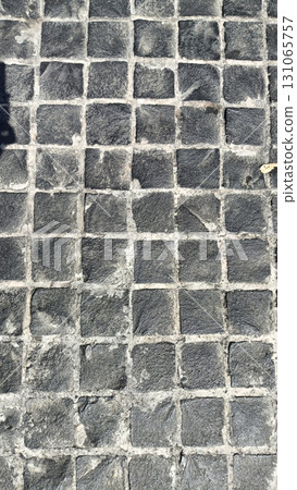 Close up view of cobblestone pavement with small, square stones arranged in grid pattern, showing texture and natural stone variations Close up view of cobblestone pavement with small, square stones arranged in grid pattern, showing texture and natural stone variations 131065757
