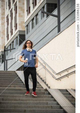 Sporty man and athlete wearing blue t-shirt running and jumping at stair in modern city. Cardio workout training. Vertical portrait. Healthy lifestyle. Wellness Sporty man and athlete wearing blue t-shirt running and jumping at stair in modern city. Cardio workout training. Vertical portrait. Healthy lifestyle. Wellness 131066138