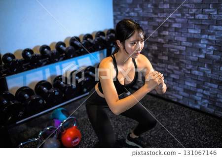 一位女士在深蹲訓練臀部。一位酷酷的女士正在健身房鍛鍊。臀部訓練。肌肉訓練女孩。 131067146