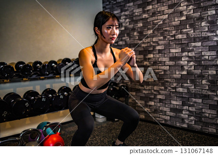 A woman training her buttocks with squats. A cool woman exercising at the gym. Hip-up. Muscle training girl. A woman training her buttocks with squats. A cool woman exercising at the gym. Hip-up. Muscle training girl. 131067148