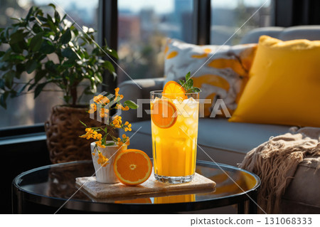 glass of orange juice and sliced oranges on table in the room, modern interior with sofa and pillows, beautiful view outside window of modern metropolis with skyscrapers glass of orange juice and sliced oranges on table in the room, modern interior with sofa and pillows, beautiful view outside window of modern metropolis with skyscrapers 131068333