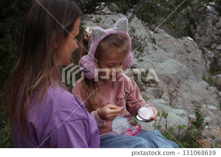 mother with daughter outside doing makeup having fun 131068639