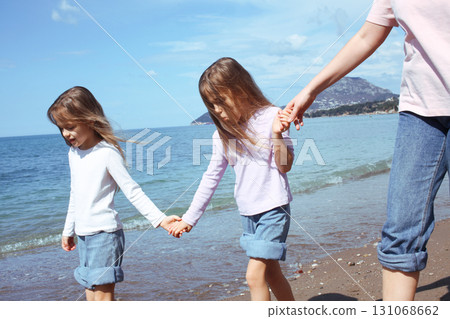 mother with twins daughters on beach 131068662