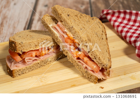 Front view of two half fresh ham and tomato sandwiches on seeded bread Front view of two half fresh ham and tomato sandwiches on seeded bread 131068691