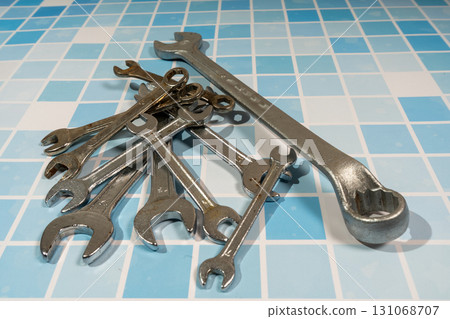 Set of wrenches lying on blue tiles representing plumbing and maintenance work 131068707