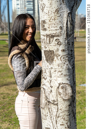 Young woman leaning against a carved tree in a park 131068718