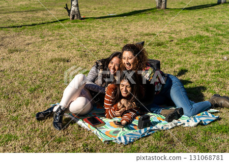 Three latin girls having fun and enjoying a picnic in the park 131068781