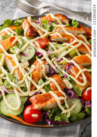 Buffalo chicken salad, featuring spicy chicken, crisp lettuce, vegetables and a creamy blue cheese dressing closeup on the plate. Vertical 131068814