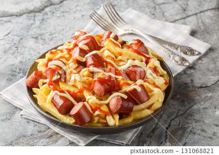 Salchipapa is a popular Peruvian recipe of French fries served with beef sausages, topped with sauce closeup on the plate. Horizontal Salchipapa is a popular Peruvian recipe of French fries served with beef sausages, topped with sauce closeup on the plate. Horizontal 131068821