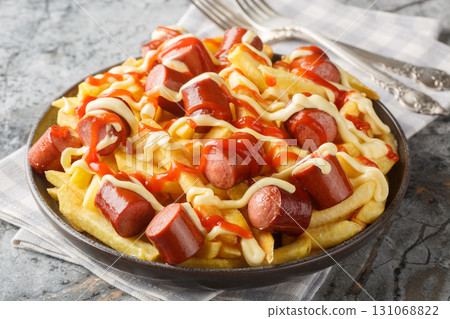 Salchipapas is a South American and Caribbean fast food dish consisting of thinly sliced pan-fried beef sausages and French fries closeup on the plate. Horizontal Salchipapas is a South American and Caribbean fast food dish consisting of thinly sliced pan-fried beef sausages and French fries closeup on the plate. Horizontal 131068822