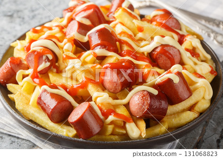 Latin America Salchipapa Sausages with fries, ketchup, mustard and mayo closeup on the plate. Horizontal Latin America Salchipapa Sausages with fries, ketchup, mustard and mayo closeup on the plate. Horizontal 131068823