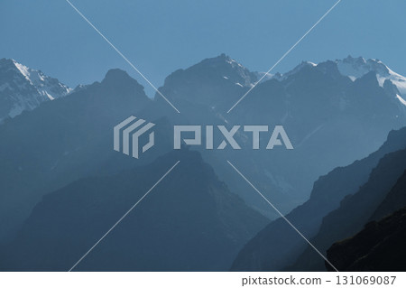 Silhouettes of snow-capped mountains and low clouds at dawn 131069087