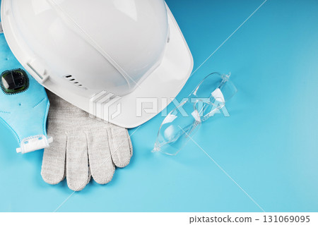 White construction worker safety helmet with personal protective equipment on blue background 131069095