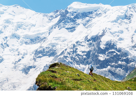 A traveler at a very high altitude with a view of the long tongue of the glacier and high snowy mountains 131069108
