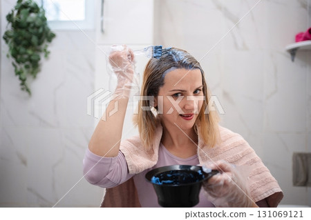 Woman dyeing her hair blue in the bathroom Woman dyeing her hair blue in the bathroom 131069121