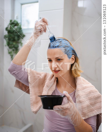 Woman dyeing her hair blue in the bathroom Woman dyeing her hair blue in the bathroom 131069123