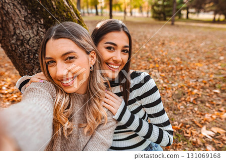 Friendship and laughter among colorful leaves in a cozy autumn park Friendship and laughter among colorful leaves in a cozy autumn park 131069168