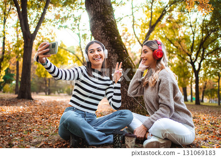 Smiles and memories shared by two girls in a cozy autumn park setting Smiles and memories shared by two girls in a cozy autumn park setting 131069183