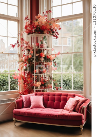 cozy interior of a living room with flowers, a red sofa and panoramic windows to the garden 131070130