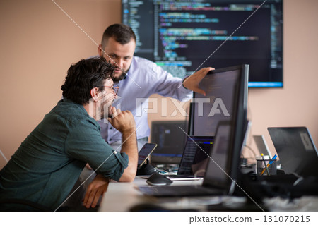 Programmers engrossed in deep collaboration, diligently working together to solve complex problems  131070215