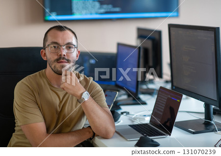 A programmer diligently testing smartphone applications while sitting in their office. A programmer diligently testing smartphone applications while sitting in their office. 131070239