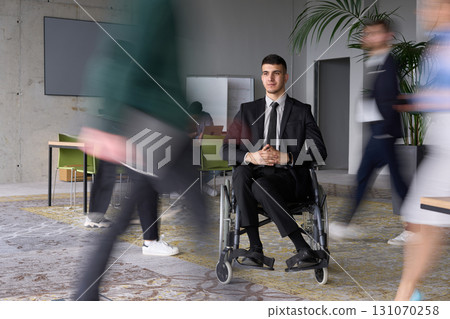 A businessman in a wheelchair navigating through a busy office, surrounded by his colleagues who are actively engaged in their work and collaboration A businessman in a wheelchair navigating through a busy office, surrounded by his colleagues who are actively engaged in their work and collaboration 131070258
