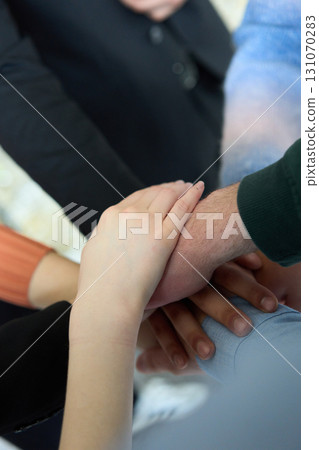 A top view of business people joining hands in a circle, symbolizing unity, collaboration, and shared success in the workplace A top view of business people joining hands in a circle, symbolizing unity, collaboration, and shared success in the workplace 131070283