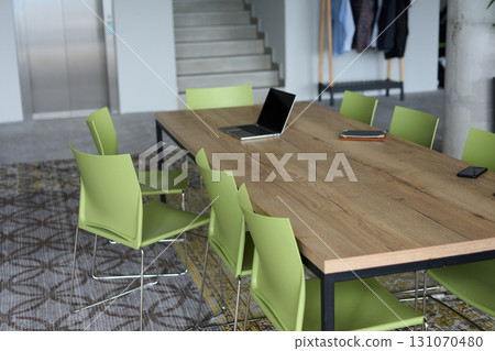 A modern and clean office space with a wooden conference table and green chairs. A modern and clean office space with a wooden conference table and green chairs. 131070480