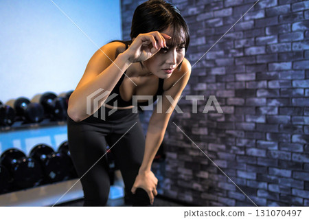Tired woman taking a break, fatigue, cool woman exercising at the gym, muscle training girl, trimmed up 131070497