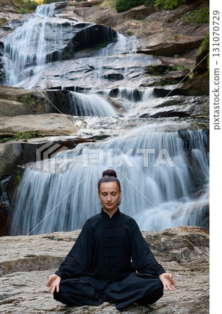 A woman sits in lotus pose, practicing yoga and tai chi under a tropical waterfall, meditating with calm strength and mindfulness, fully connected to the energy of nature, tranquility and inner A woman sits in lotus pose, practicing yoga and tai chi under a tropical waterfall, meditating with calm strength and mindfulness, fully connected to the energy of nature, tranquility and inner 131070729