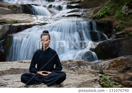 A woman sits in lotus pose, practicing yoga and tai chi under a tropical waterfall, meditating with calm strength and mindfulness, fully connected to the energy of nature, tranquility and inner A woman sits in lotus pose, practicing yoga and tai chi under a tropical waterfall, meditating with calm strength and mindfulness, fully connected to the energy of nature, tranquility and inner 131070740