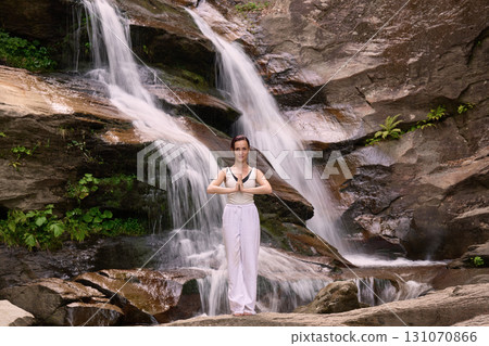 woman performing slow tai chi movements near a waterfall and river at sunset capturing harmony balance and fitness in nature woman performing slow tai chi movements near a waterfall and river at sunset capturing harmony balance and fitness in nature 131070866