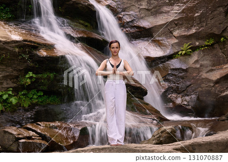 woman performing slow tai chi movements near a waterfall and river at sunset capturing harmony balance and fitness in nature 131070887