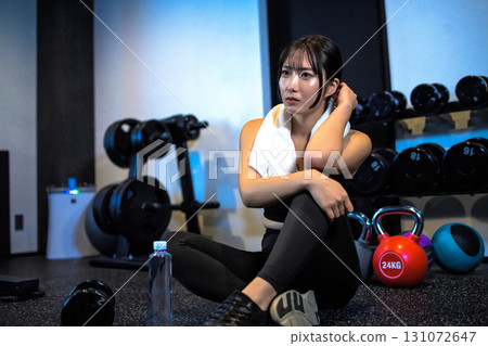 A woman sitting and resting after exercising. A cool woman exercising at the gym. Posing 131072647