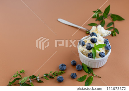 Seasonal composition cottage cheese blueberries and mint on a warm background Seasonal composition cottage cheese blueberries and mint on a warm background 131072872