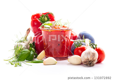 Glass of tomato sauce surrounded by fresh vegetables 131072892