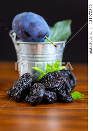 Organic dried prunes with natural plum and green leaves Organic dried prunes with natural plum and green leaves 131072896